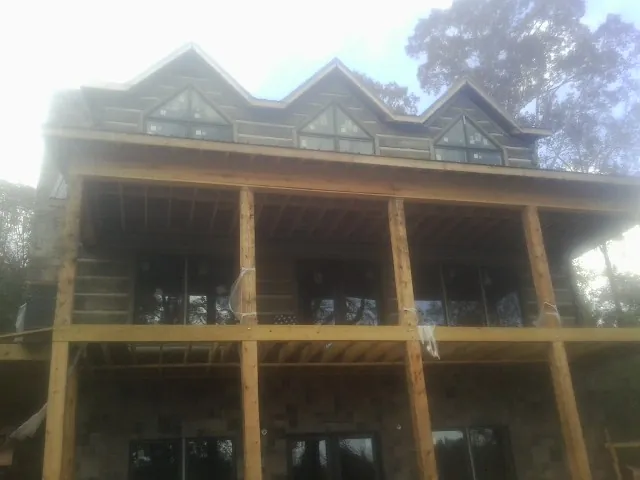 Dormers and porch framing on a large log home under construction — Roof Coating work by our crew in Beacon