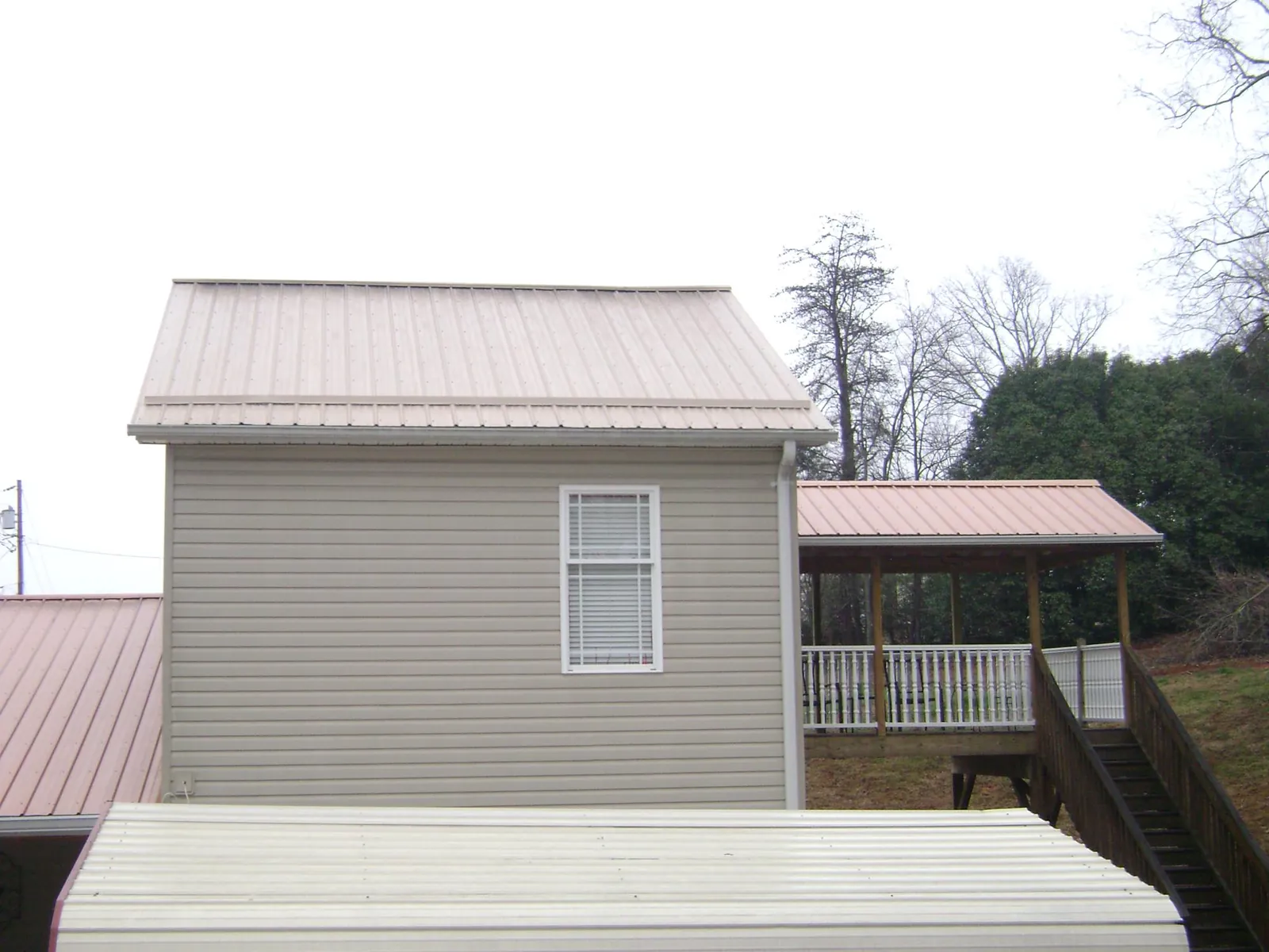 Tan metal roofs on a two story addition and attached porch, from a Roof Replacement job in Beacon